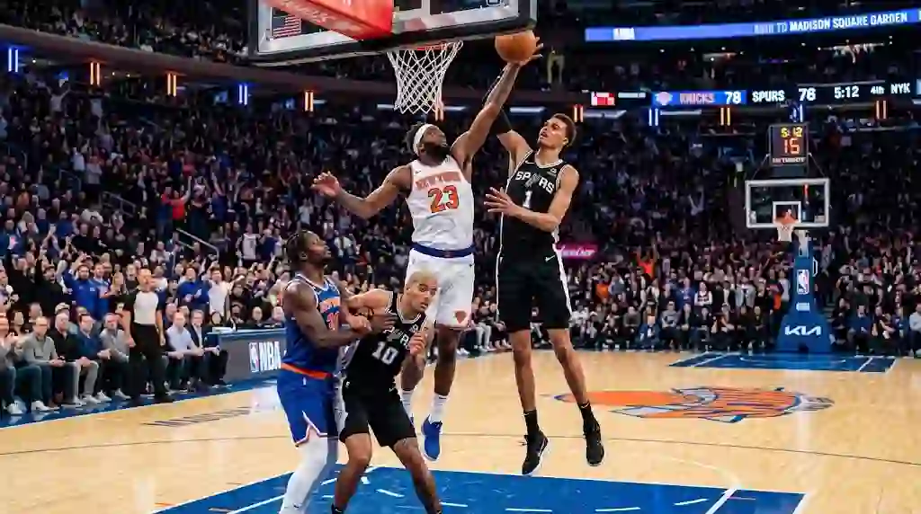 Action-packed NBA game between the New York Knicks and San Antonio Spurs, showing players leaping for a rebound near the basket inside a packed arena.